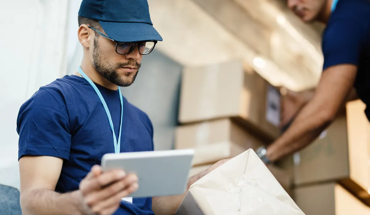young-delivery-man-using-touchpad-while-bg